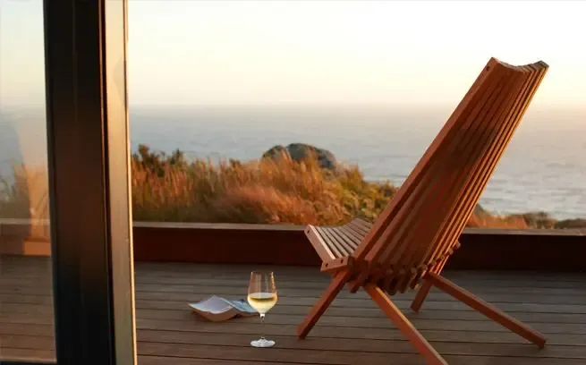 A deck chair and wine glasses overlooking the Pacific at Timber Cove Resort