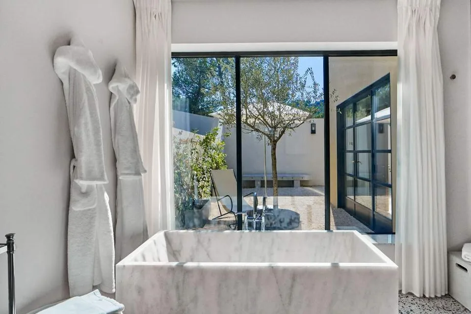 Marble bathroom opening towards a private courtyard at Villa La Coste