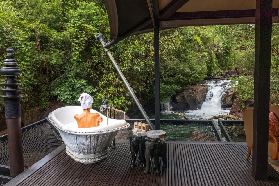 Outdoor bath and deck overlooking a waterfall at Shinta Mani Wild