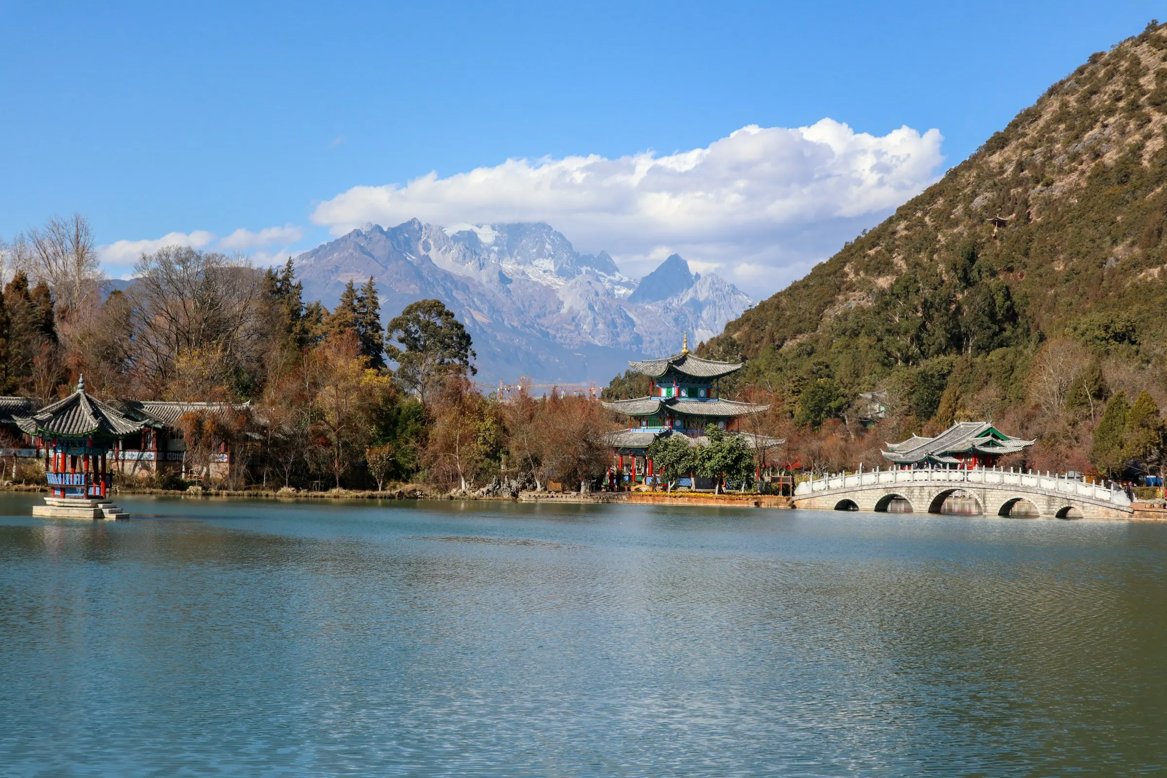 The arched marble bridge and pavilions of Black Dragon Pool in Lijiang, with the snows of Jade Dragon Snow Mountain beyond.