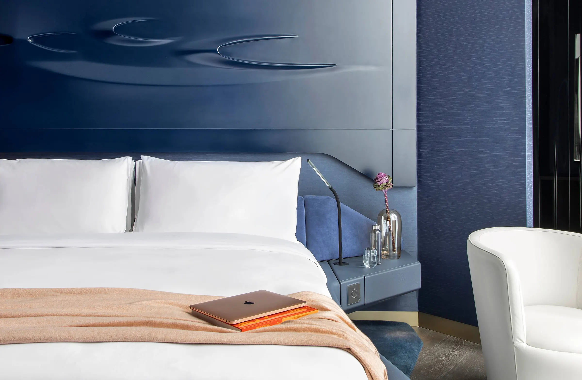 Guest bedroom with curved navy headboard at ME Dubai
