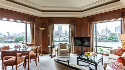 Wood-panelled suite sitting and dining area overlooking the river at The Peninsula Bangkok
