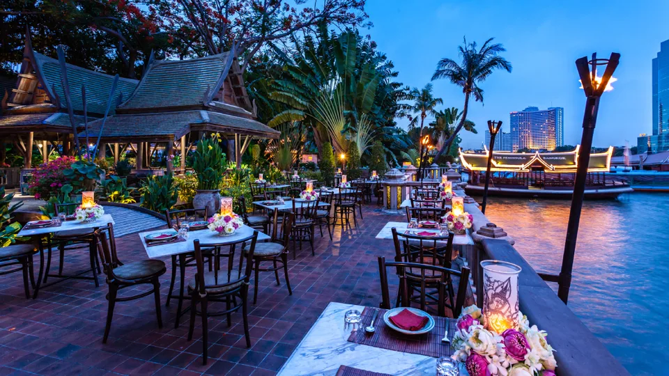 Thiptara tables beside the Chao Phraya River at dusk at The Peninsula Bangkok