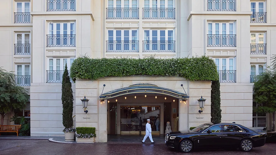 The Peninsula Beverly Hills entrance with a hotel page and a chauffeured car
