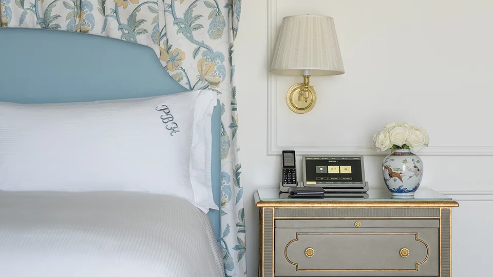 Blue and white headboard, monogrammed pillow and bedside details in a Grand Deluxe Room at The Peninsula Beverly Hills