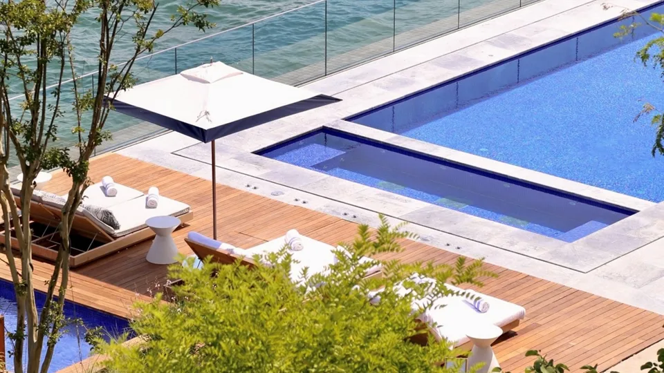 Blue outdoor pool and sun loungers beside the Bosphorus at The Peninsula Istanbul
